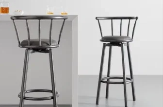 Zwei schwarze Bessagi Barhocker mit gepolstertem Sitz vor einer weißen Theke