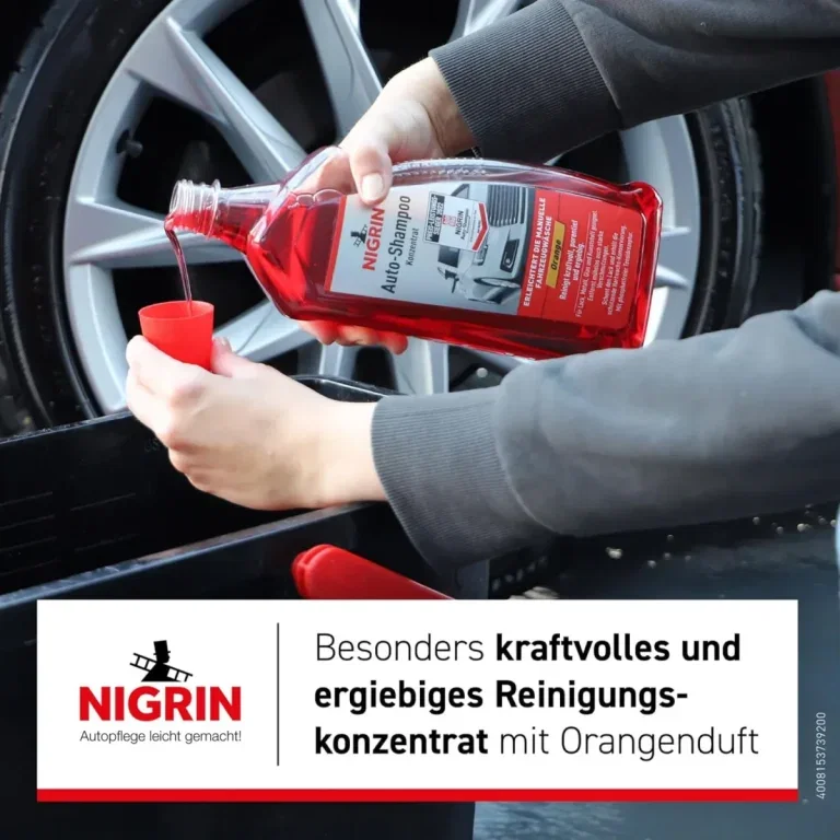 Ein Mann hält eine rote Flasche NIGRIN Autoshampoo Konzentrat und gießt es in einen kleinen roten Becher, im Hintergrund ein Auto