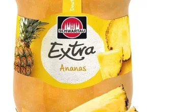 Glas Schwartau Extra Ananas Konfitüre mit schwarzem Deckel und frischen Ananasstücken davor