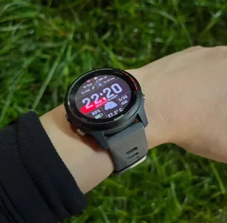 Garmin Forerunner 255 Smartwatch am Handgelenk mit aktivem Display vor grünem Gras