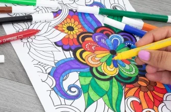Hand färbt ein Blumen-Mandala mit gelbem Pelikan-Maler, daneben liegen weitere Stifte auf grauem Holz.