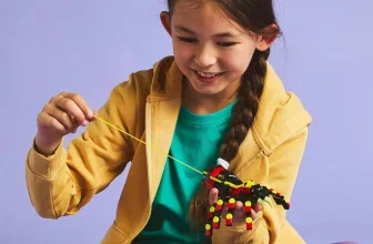 Mädchen in gelber Jacke hält LEGO-Spinne an gelbem Faden