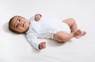 Baby in weißem Langarm-Body auf hellem Untergrund