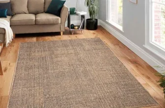 Beige Jute-Teppich Amara in einem hellen Wohnzimmer vor einem braunen Sofa und auf Parkettboden