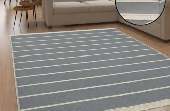Grauer gestreifter Teppich mit Fransen in einem Wohnzimmer vor einem hellen Sofa