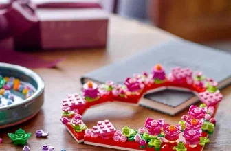 LEGO Herz-Deko auf Holztisch mit Schale voller Steine und verpacktem Geschenk im Hintergrund