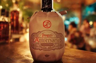 Ein Flasche Rum in brauner Ledertasche auf einem Holztisch.