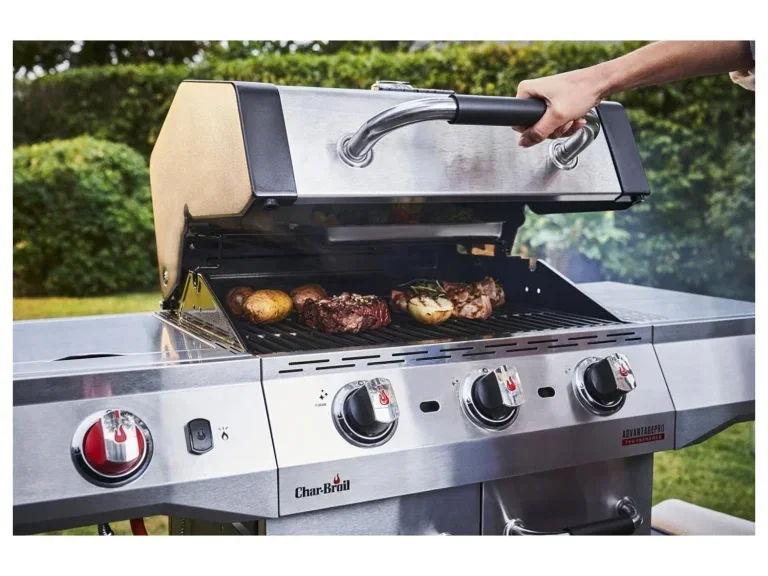 Ein silberner Gasgrill mit geöffnetem Deckel, Grillgut auf dem Rost, im Hintergrund ein gepflegter Garten.