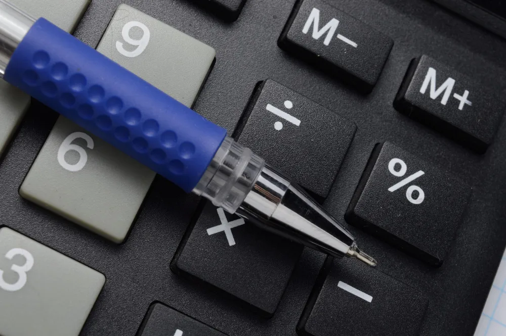 Taschenrechner mit Prozenttaste und Kugelschreiber als Symbol für Preisberechnung und dynamisches Pricing