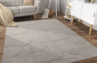 Grauer Teppich mit geometrischem Muster auf Holzboden vor einem hellen Sofa