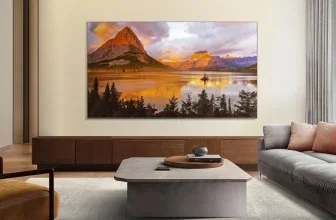 Ein 65-Zoll-QLED-Fernseher in einem Wohnzimmer, auf dem ein Bergpanorama mit See und Bäumen zu sehen ist.