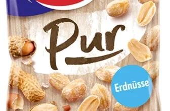 Eine Tüte Erdnüsse mit blauem oberen Abschnitt, rotem Logo und der Aufschrift 'Pur' sowie verstreuten Erdnüssen.