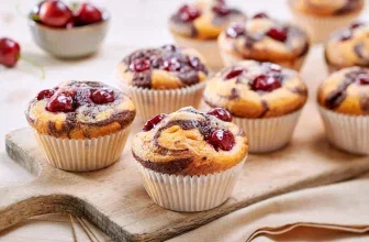 Ein Tablett mit Marmormuffins, die mit Kirschen belegt sind.