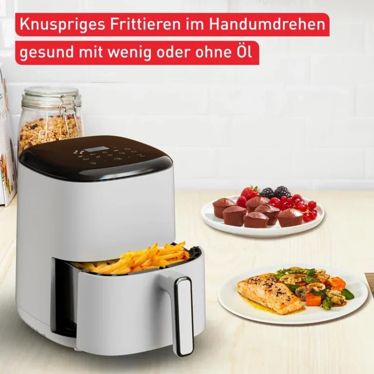 Weißer Airfryer mit herausgezogenem Korb voller Pommes, daneben Teller mit Fisch, Gemüse und Muffins.