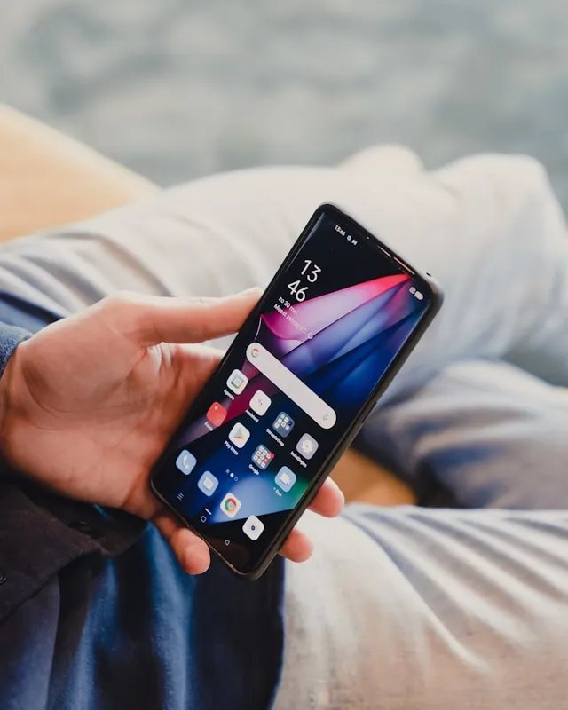 dylan calluy Nc3zc7ClxMI unsplash Person hält ein Smartphone in der Hand und prüft Apps auf dem Startbildschirm