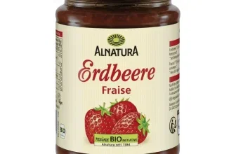 Ein Glas Alnatura Bio Fruchtaufstrich Erdbeere mit goldenen Deckel und beige Etikett, darauf drei Erdbeeren und der Schriftzug Alnatura