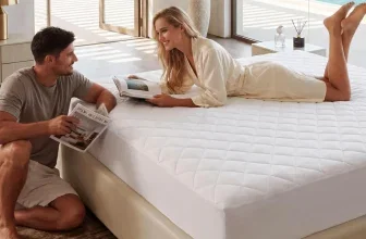 Ein Paar liegt auf einem großen, weißen Bett und liest ein Buch, im Hintergrund ein Meer