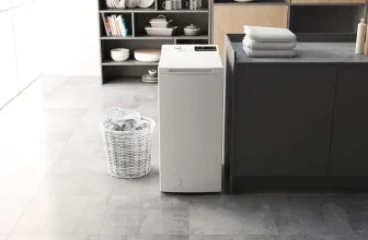Weiße Waschmaschine neben einem Wäschekorb in einem hellen Raum.