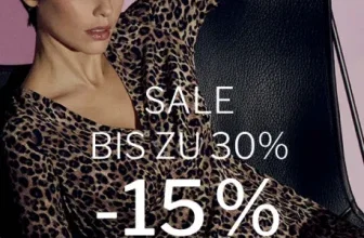 Eine Frau sitzt auf einem schwarzen Stuhl, trägt ein Leopardenmuster-Kleid und schaut in die Kamera.