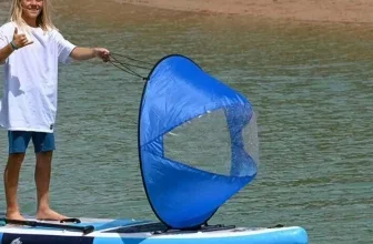 Ein SUP-Board im Wasser mit einem Mann darauf, der ein Segel hält
