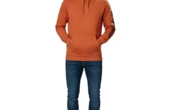 Ein Mann trägt einen orangefarbenen Hoodie mit Kapuze, blauen Jeans und weißen Sneakern