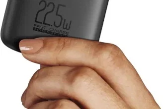 Eine Hand hält eine schwarze Powerbank mit blauem Display, das 100% anzeigt.