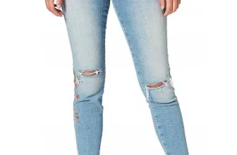 Eine Frau trägt blaue Skinny-Fit-Jeans mit floralen Stickereien an den Knien