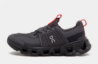 Ein schwarzer Laufschuh für Kinder mit roten Akzenten und dem On-Logo