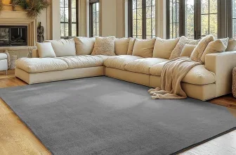 Ein grauer Teppich in einem Wohnzimmer mit hellen Möbeln und großen Fenstern.