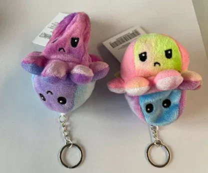 Zwei bunte Oktopus-Schlüsselanhänger mit traurigen Gesichtern, im Hintergrund ein weißer Zettel mit Barcode