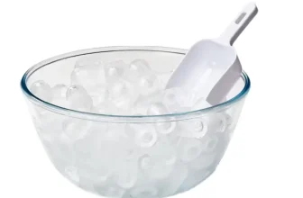 Ein Glas mit Eiswürfeln und einem weißen Eisportionierer