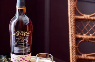 Eine Flasche Zacapa La Armonia Ultra-Premium-Rum neben einem Glas auf einem goldenen Tablett.
