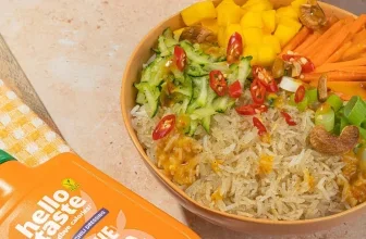 Eine Flasche Mango-Chili Dressing neben einem Salat mit Reis, Mango, Chili und Gemüse.