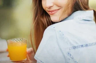 Frau mit rotem Haar hält Glas Orangensaft. Text: Deine Gesundheitsroutine, Vitamin C Power.