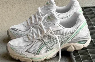 Ein Paar weiße Sneaker mit grünen Akzenten auf einem grauen Boden