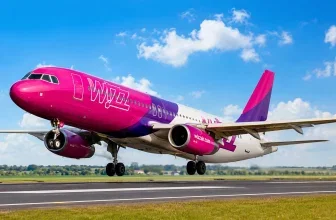 Ein pinkes Flugzeug mit dem Schriftzug Wizz auf dem Rumpf landet auf einer Start- und Landebahn