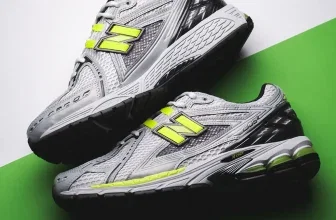 Detailaufnahme von grauen New Balance U1906 Sneakern mit gelbem N-Logo auf grünem Hintergrund
