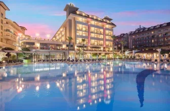 Hotelkomplex Aydinbey Kings Palace mit beleuchteten Gebäuden und Pool bei Dämmerung