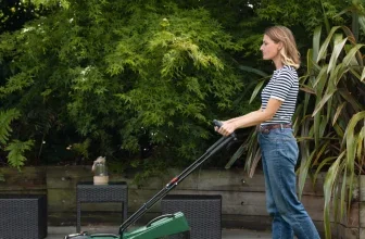 Frau schiebt grünen Bosch Akku-Rasenmäher auf Wiese im Garten