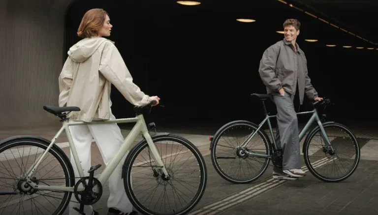 Zwei Personen mit Tenways CGO600 E-Bikes in hellgrün und dunkelgrau in einer urbanen Umgebung.