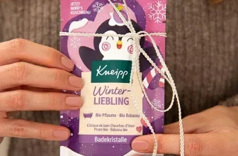 Hände halten eine verpackte Tube Kneipp Badekristalle Winterliebling mit Pinguin-Motiv