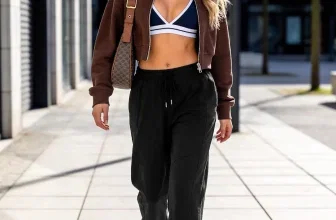 Model trägt schwarze Jogginghose mit brauner Jacke und Sneakern auf städtischem Gehweg