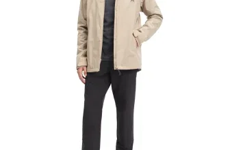 Modell trägt beige McKINLEY Herren Doppeljacke Tessi 3:1 mit Kapuze und schwarzer Hose