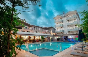 Außenansicht des Hotels mit Swimmingpool, Liegestühlen und Restaurantbereich bei Dämmerung