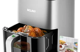 Silberne ROJNY Heißluftfritteuse mit geöffnetem Korb, gefüllt mit gebratenem Hähnchen, und Rezeptbuch daneben