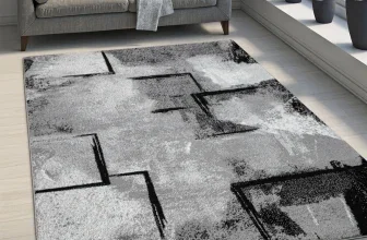 Schwarz-weißer Teppich mit geometrischem Muster vor grauem Sofa und Fensterbank