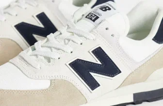 Detaillierte Nahaufnahme eines New Balance 574 Sneakers in Weiß und Beige mit dunkelblauem N-Logo und weißer Sohle.