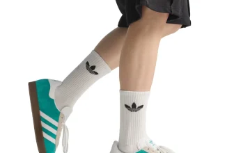 Model trägt türkis-grüne Adidas Gazelle Sneaker mit Liverpool FC Schriftzug und Gummi-Sohle