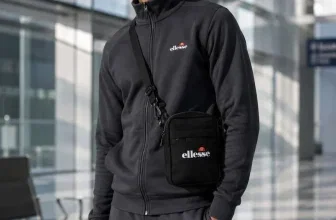 Model trägt schwarze Ellesse Manifatto Umhängetasche im modernen Gebäude