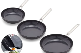 Drei schwarze Greenpan Omega Bratpfannen mit weißen Griffen auf schwarzem Hintergrund